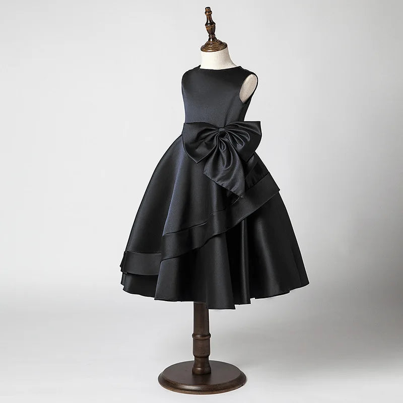 Black dress with a large bow on a mannequin against a gray background