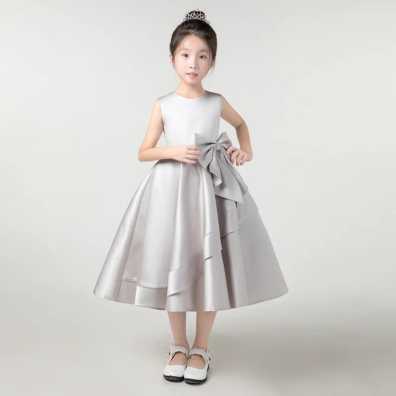 Young girl wearing a silver dress with a bow on a white background