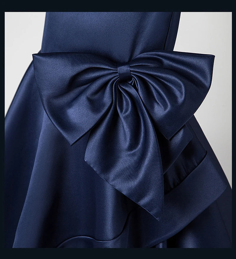 Navy blue dress with a large bow detail on a light gray background