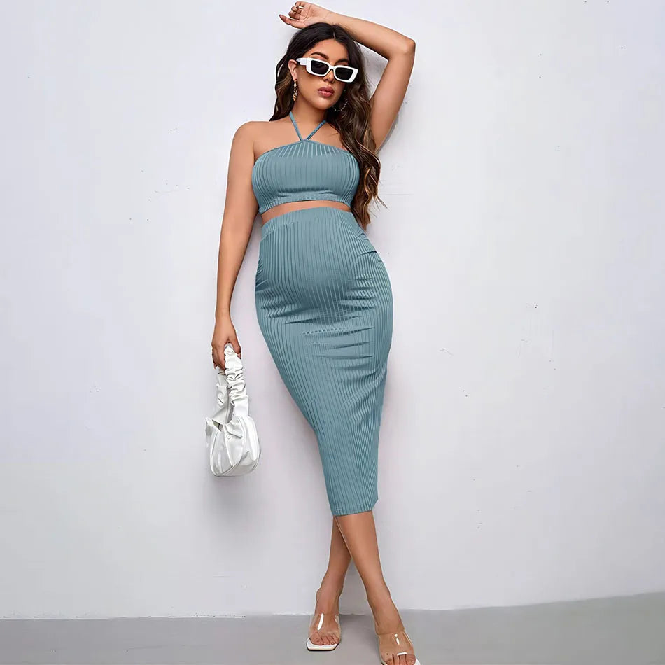 Woman wearing a teal ribbed dress with sunglasses and a white handbag against a light gray background