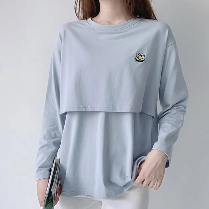 Light blue long-sleeve shirt with a small logo worn by a person on a plain background